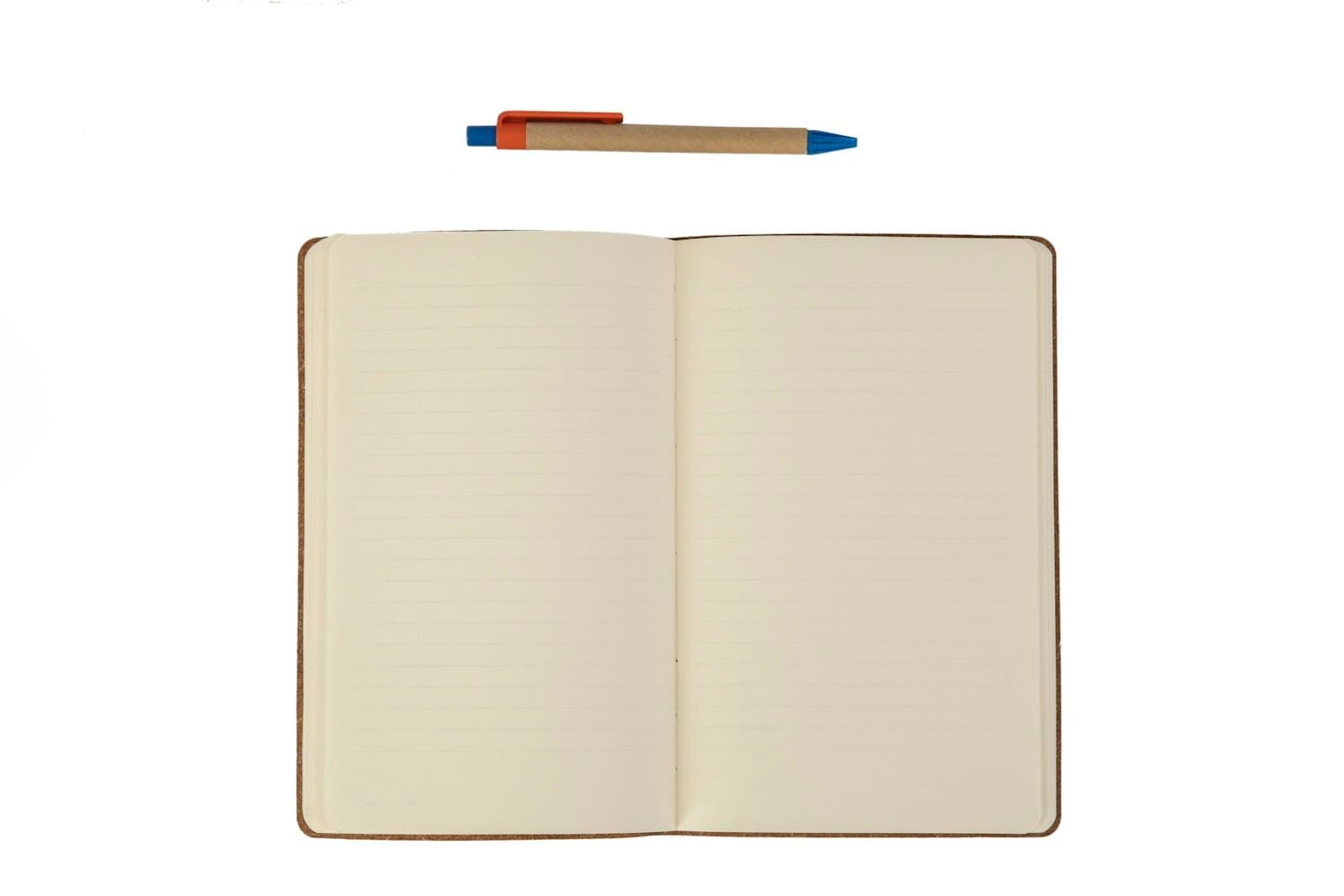 Beyaz zemin üzerinde açık duran çizgili bir defter ve üstünde duran karton gövdeli tükenmez kalem